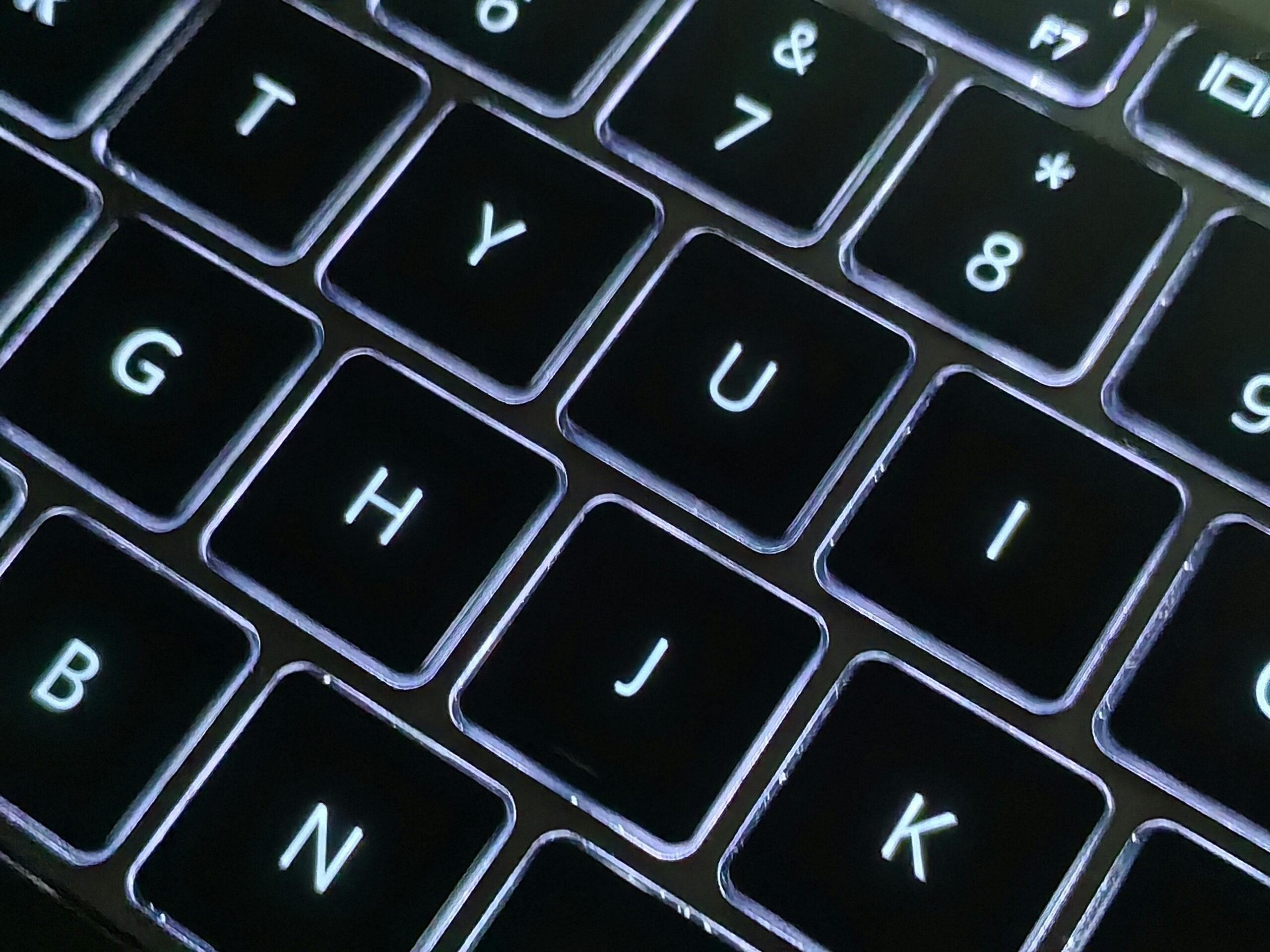 A detailed close-up photo of a backlit laptop keyboard with glowing keys, showcasing modern technology.